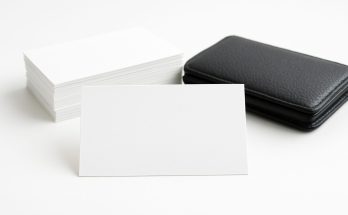 Stack of blank business cards next to a black cardholder on a white background
